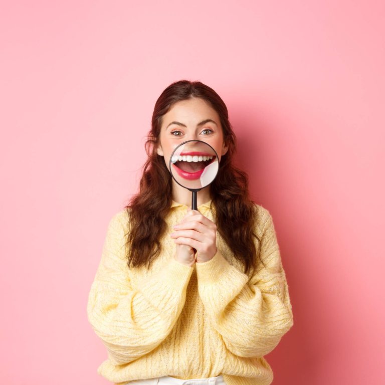 A young woman smiling confidently, showing her teeth after successful Invisalign treatment.