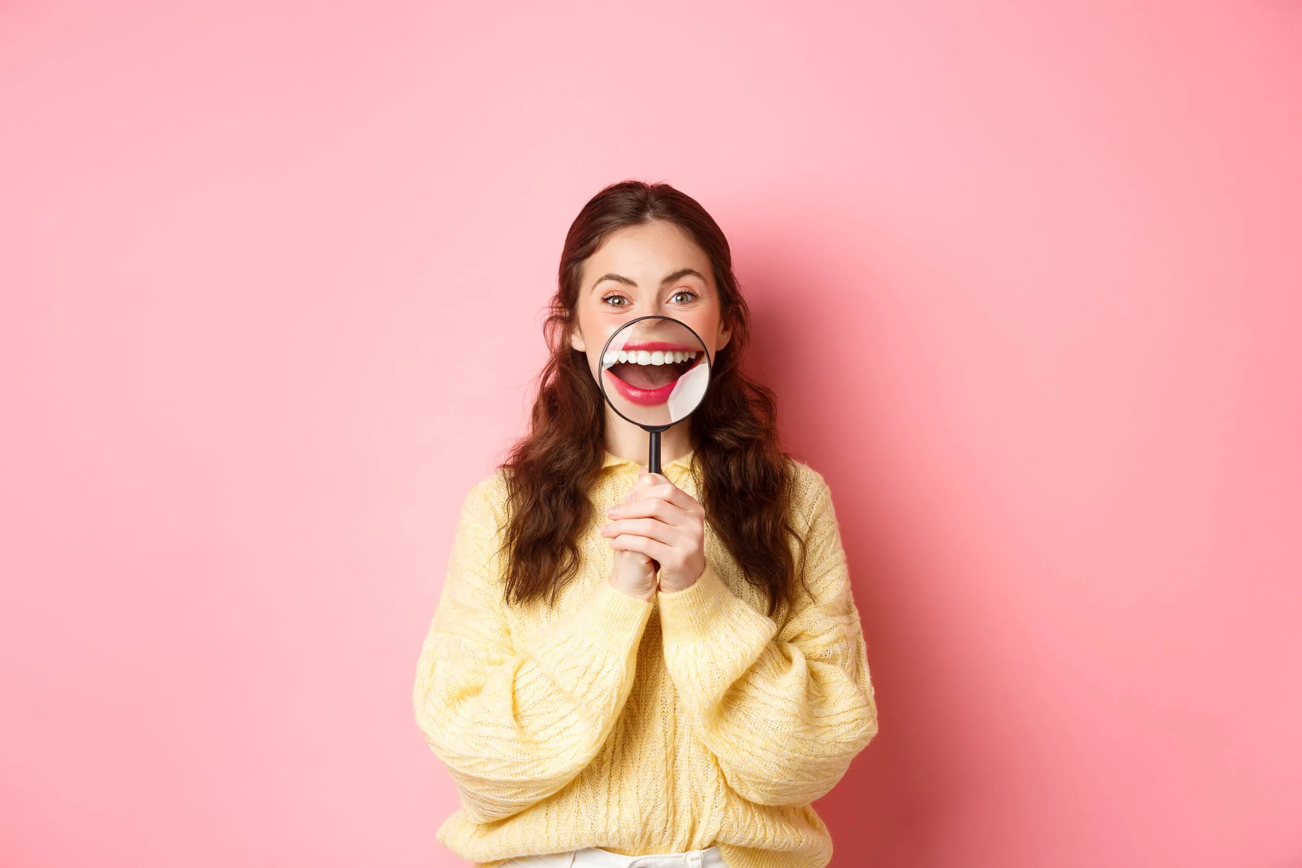 A young woman smiling confidently, showing her teeth after successful Invisalign treatment.